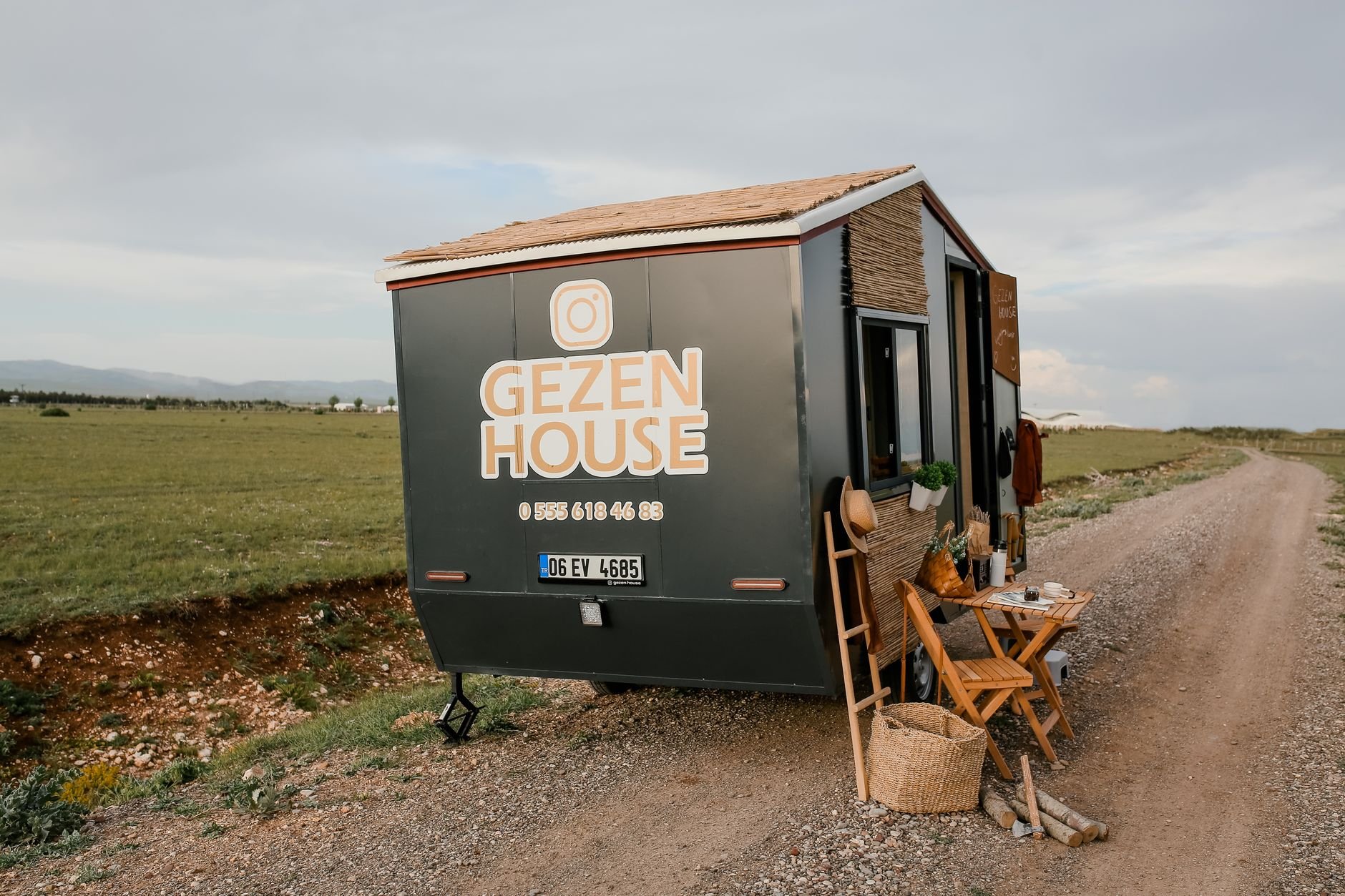 A modern mobile tiny house by a rural road in scenic countryside, ideal for off-grid living.